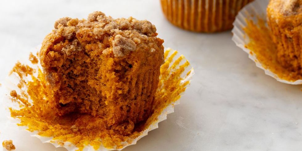 Pumpkin spice muffin on a white table with a bite taken 