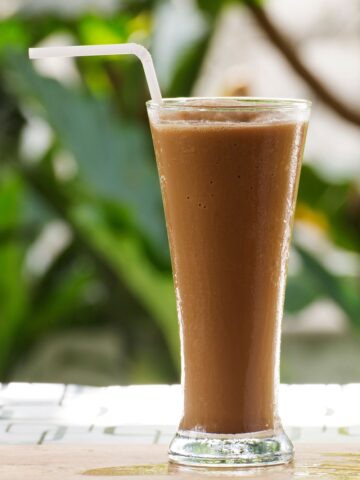 Tall glass of a coffee smoothie with a white straw