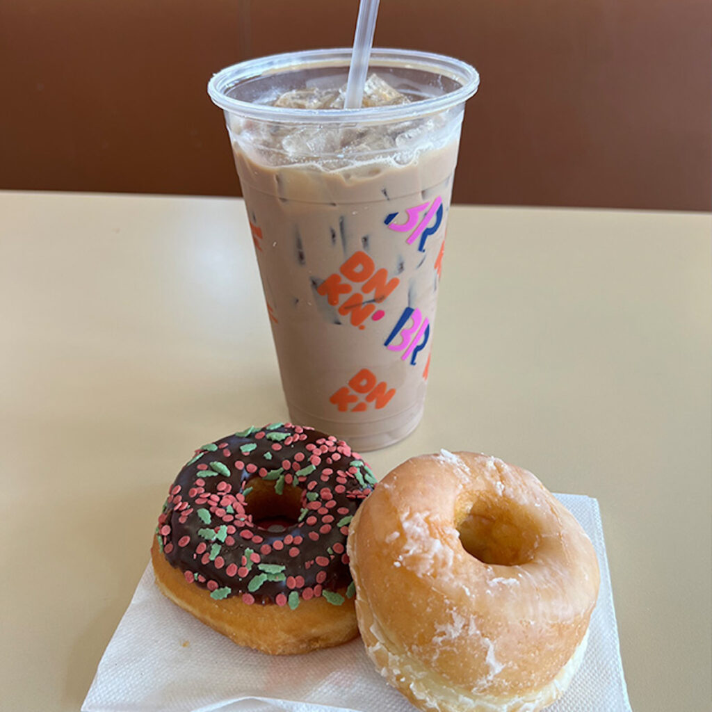 cup of dunkin donuts iced coffee with a chocolate sprinkled donut and glazed donut