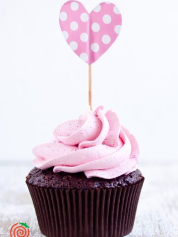 chocolate cupcake with pink frosting and a pink heart cupcake topper
