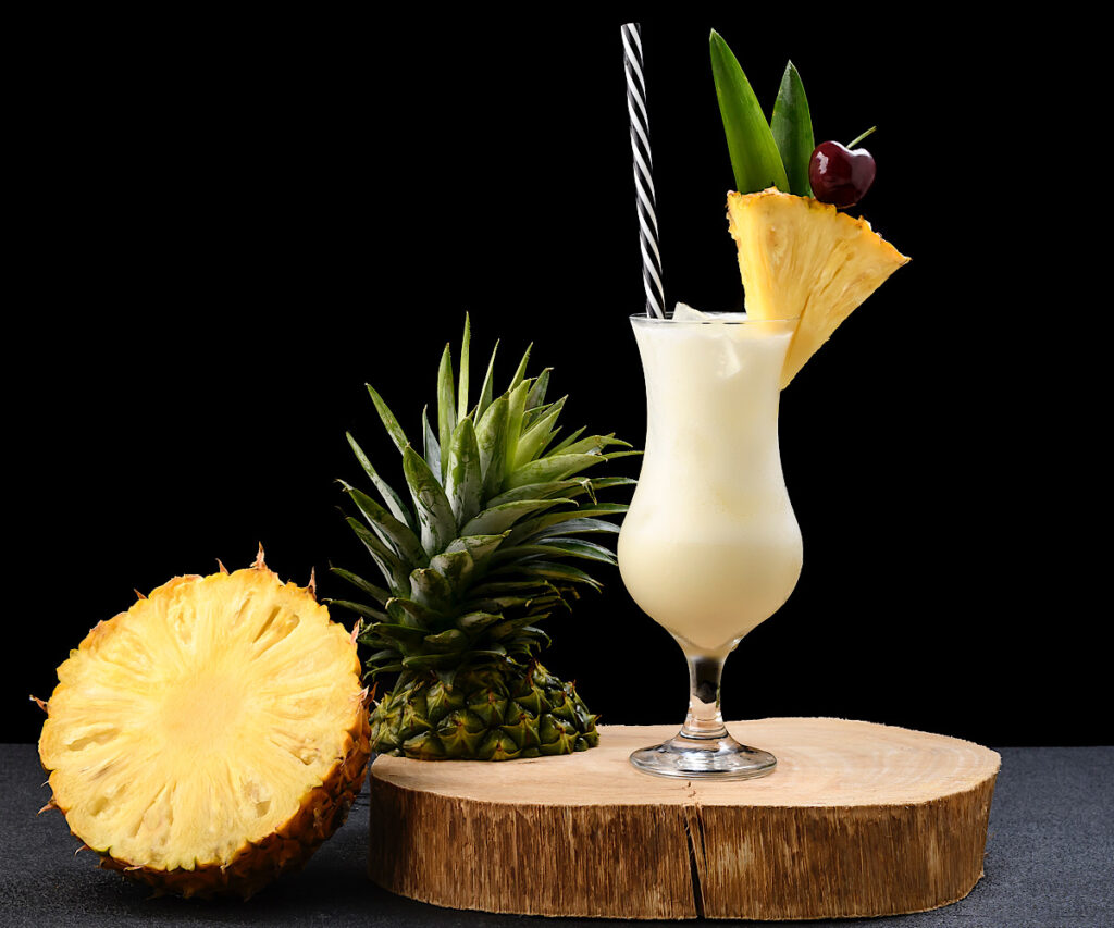 frozen pina colada from flavor portal recipe garnished with a pineapple wedge next to a sliced pineapple