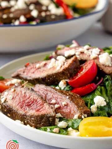 slices of grilled balsamic marinated steak on a salad bed
