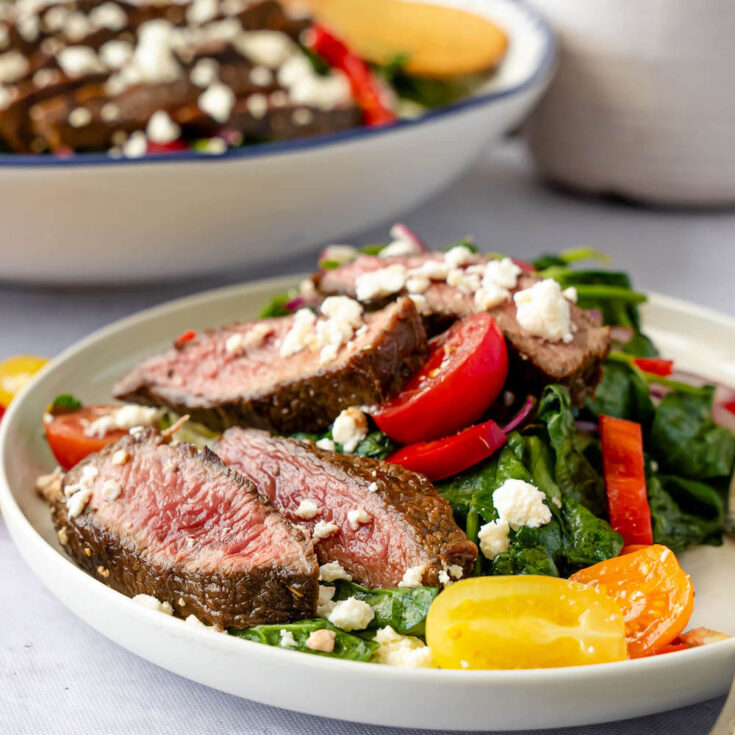 slices of grilled balsamic marinated steak on a salad with blue cheese sprinkles