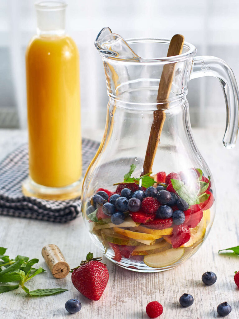 mint berry fruit ingredients in a glass pitcher with wooden spoon