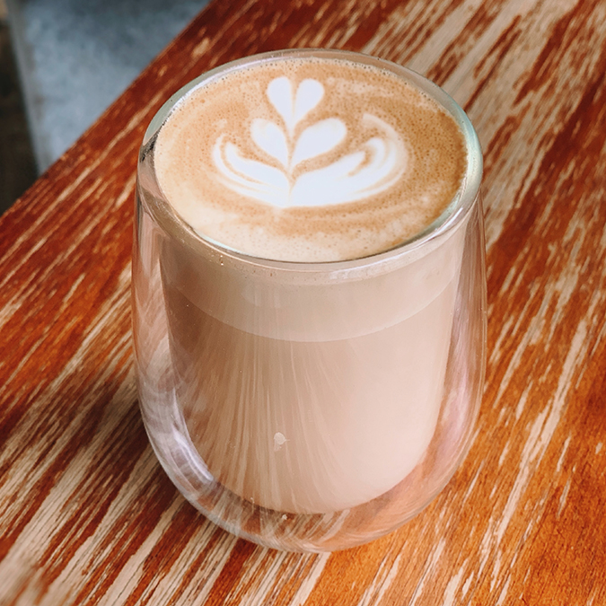 glass of breve coffee on a wood counter