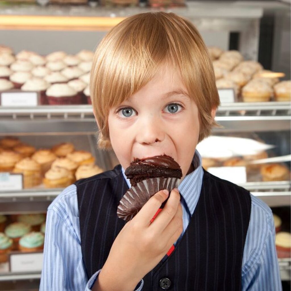 young boy eating a chocolate cupcake