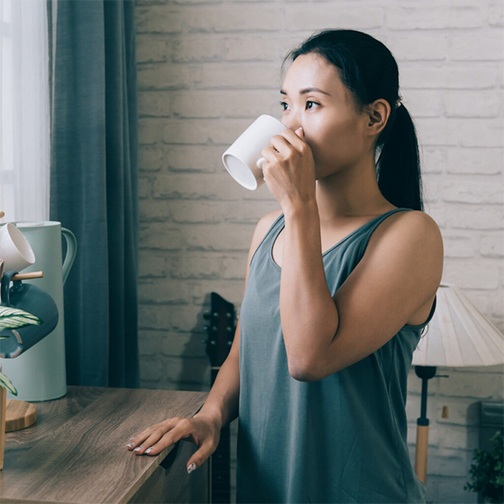 woman in workout clothes drinking a cup of coffee
