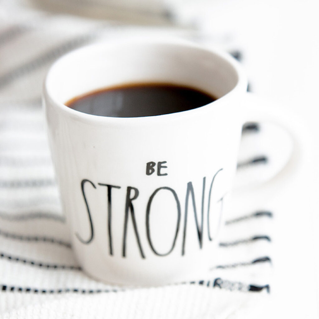 black coffee in a mug that says 'be strong'