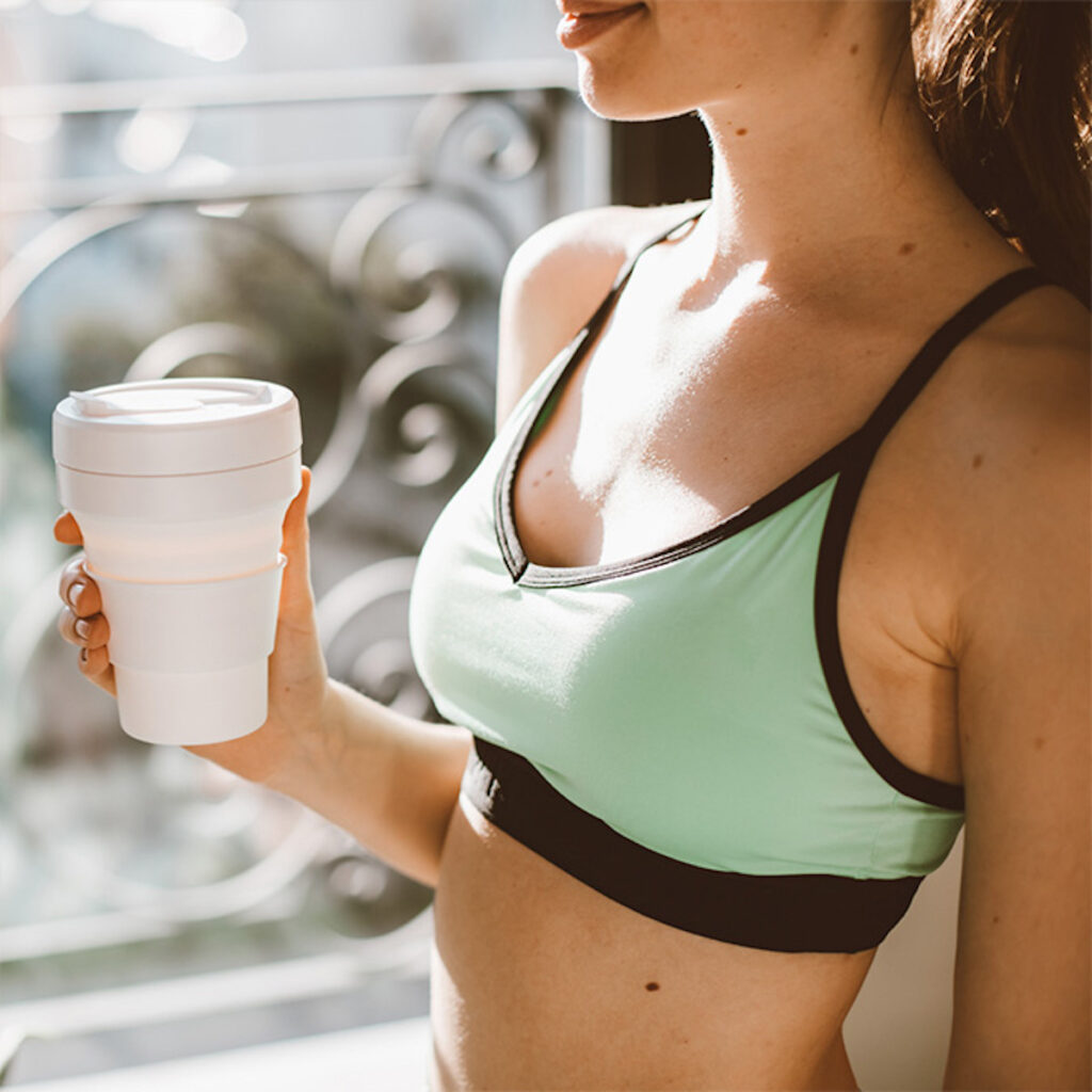 woman in sports bra with cup of coffee