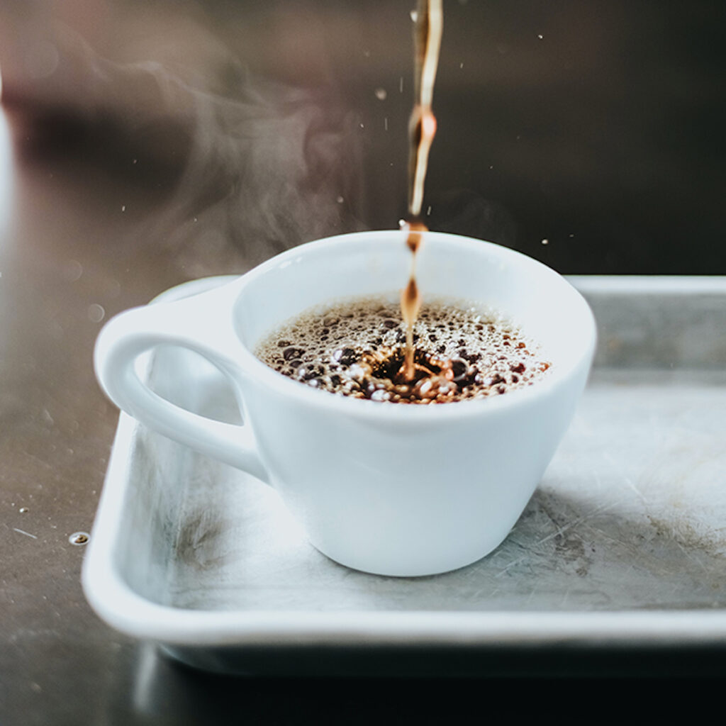coffee pouring into a small white ceramic coffee cup