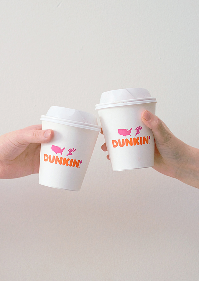 hands tapping two cups of dunkin donuts coffee together