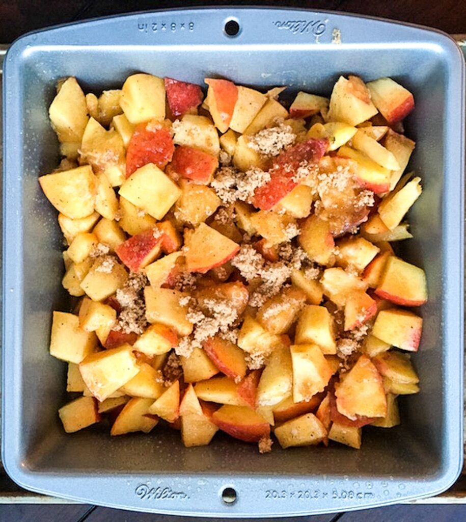 homemade peach cobbler ingredients in a baking pan ready to cook
