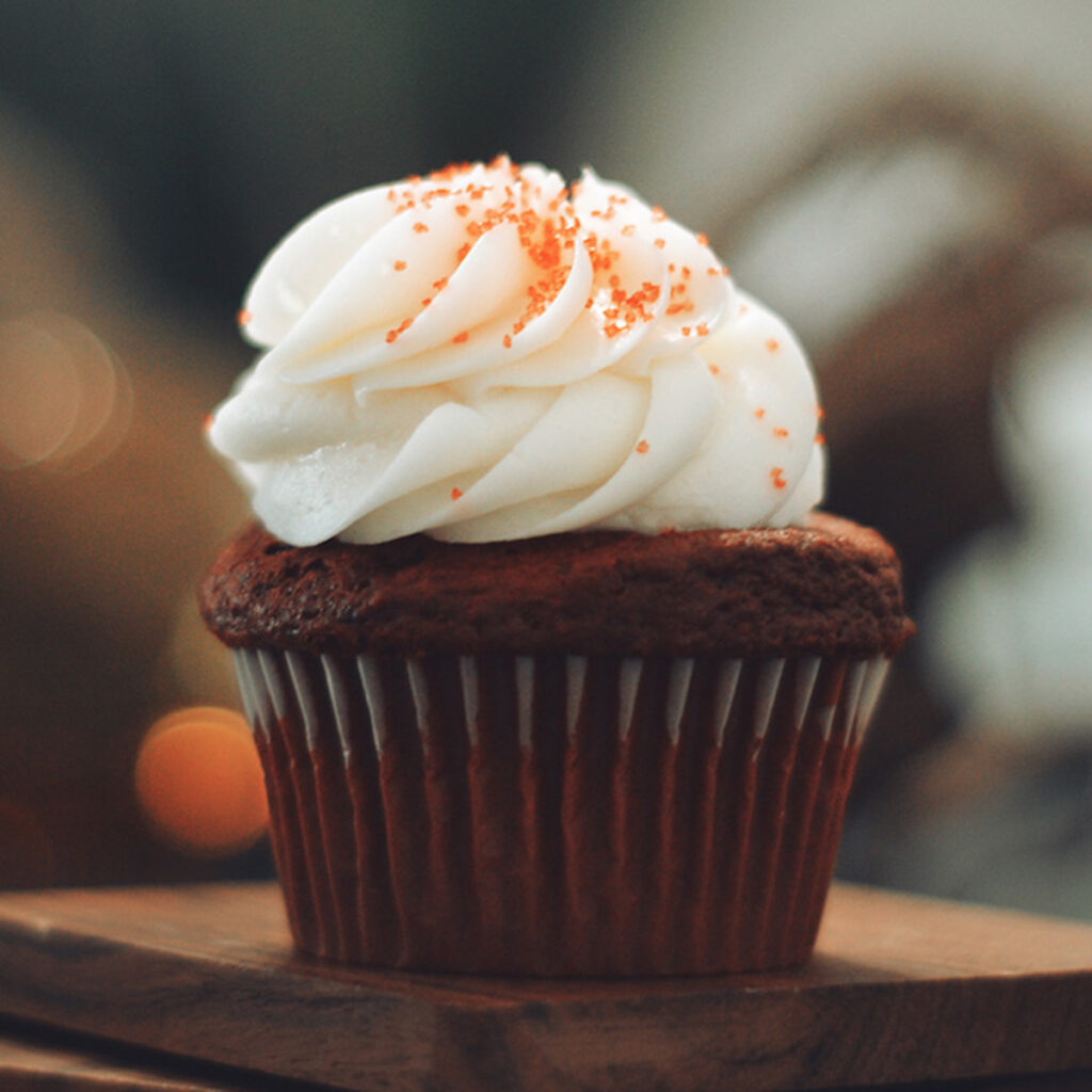 chocolate cupcake with white swirled frosting and orange sprinkles