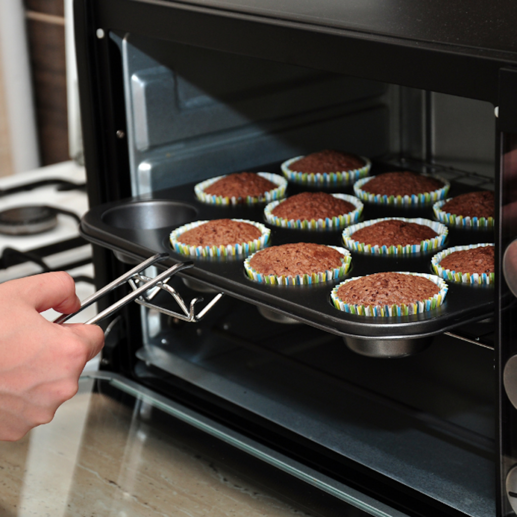 cupcake pan full of cupcakes being pulled from the oven