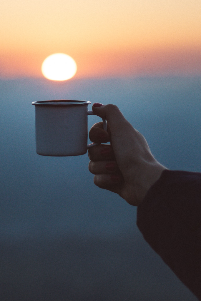 mug of coffee in front of a rising sun