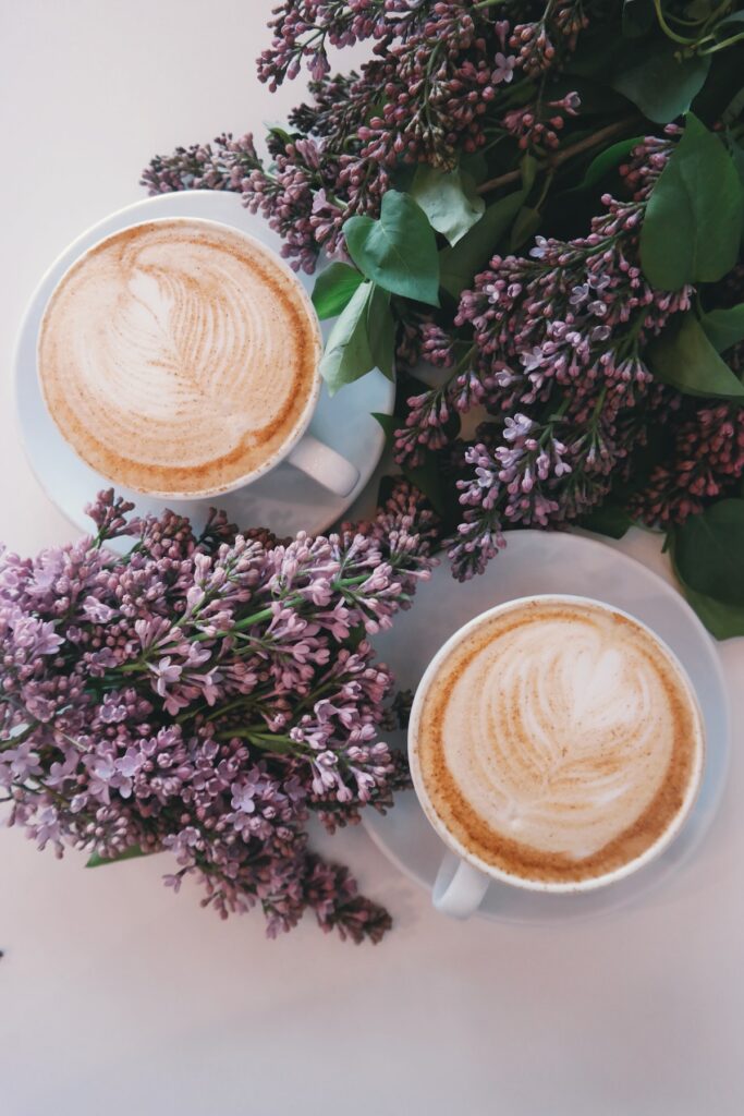 two cups of coffee surrounded by purple flowers