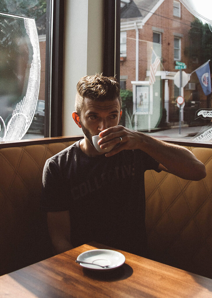 man in a cafe booth drinking coffee