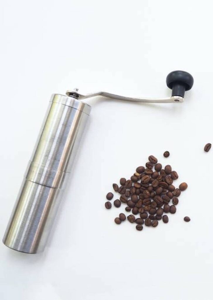 manual coffee grinder next to a pile of coffee beans