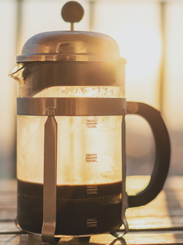 sun shining through a French press with cold brew coffee in it