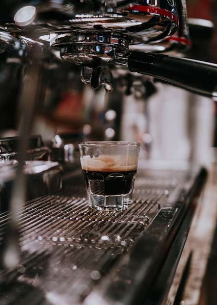 shot of espresso in a glass on the drain pan of an espresso machine