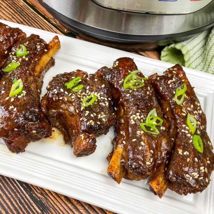 asian style sticky ribs on a white plate next to an Instant Pot