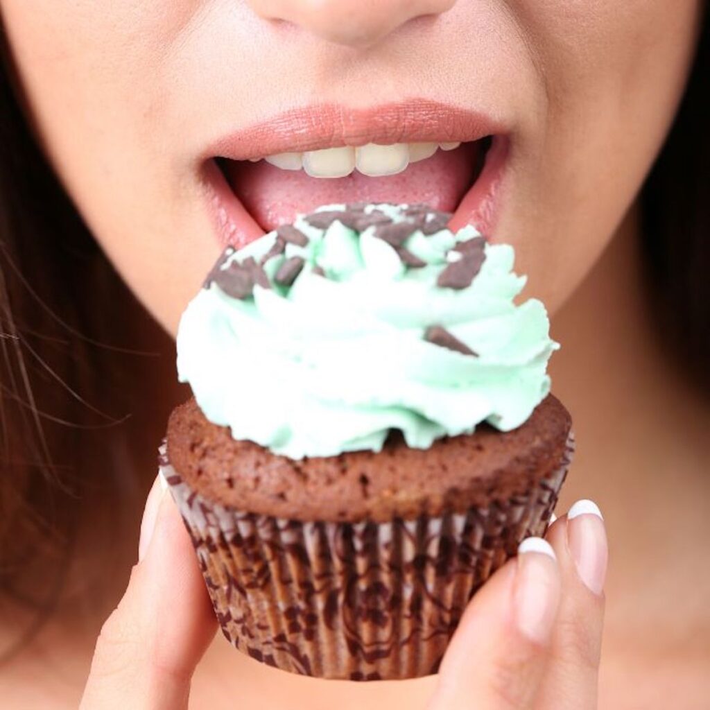 woman about to take a bite out of a chocolate cupcake