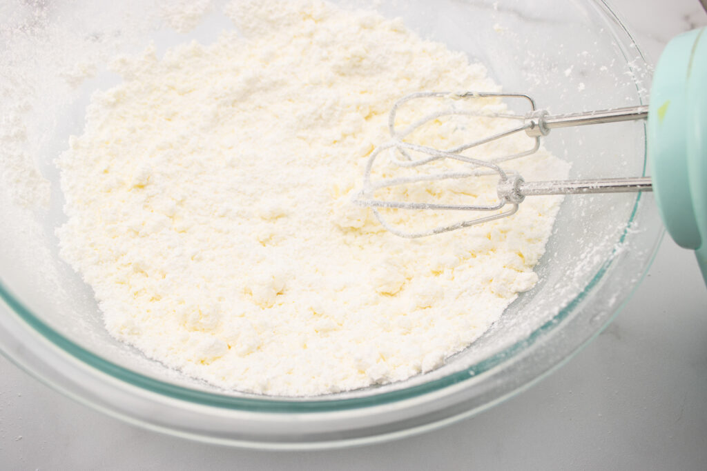 buttercream frosting recipe mix ingredients to desired consistency process photo, clear bowl on white background