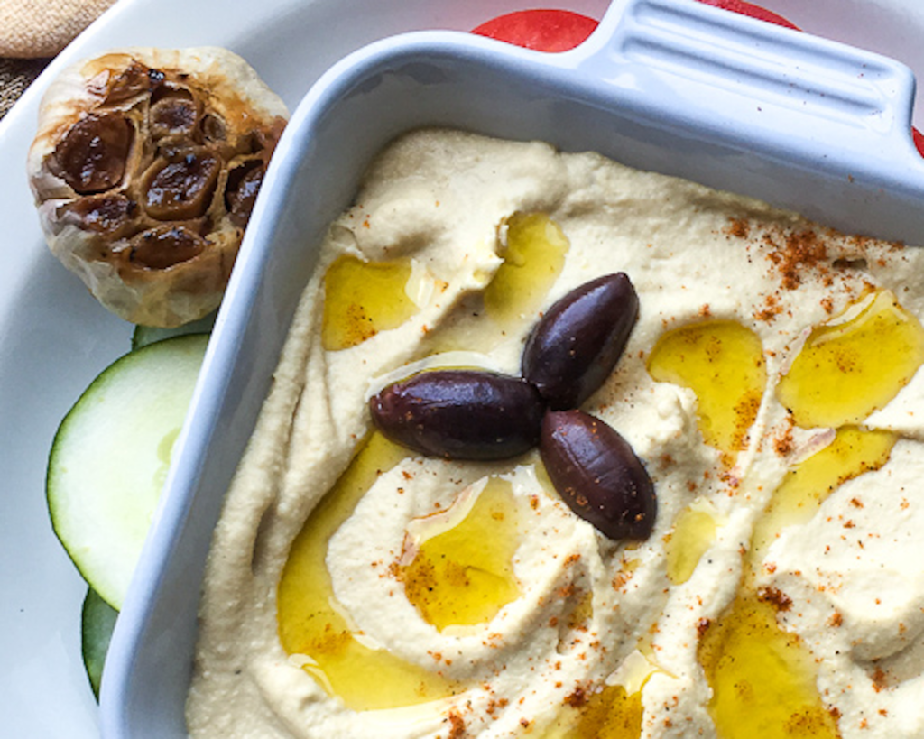 garlic roasted hummus in white dish with kalamata olives and drizzled olive oil for flavor portal recipe