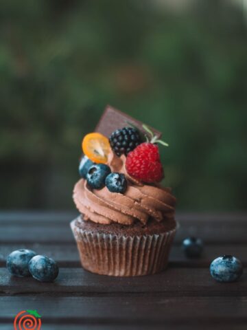 chocolate cupcake with chocolate frosting toppied aith eblueberries, blackberries and raspberries
