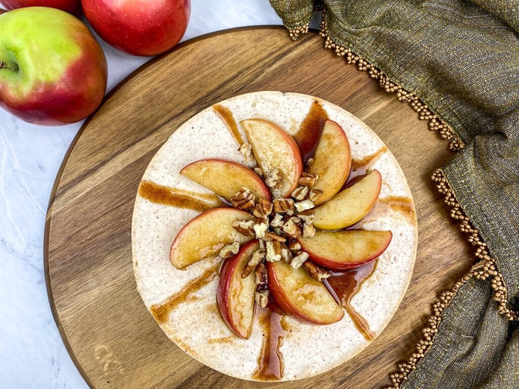 Instant pot apple cinnamon cheesecake on cutting board with apple slices