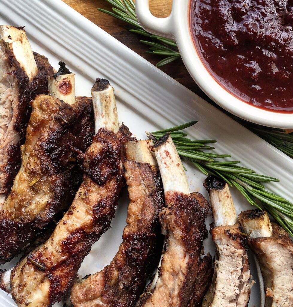 Instant pot baby back ribs on a white plate garnished with bbq sauce and rosemary