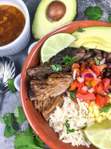 top view instant pot carnitas bowl from Flavor Portal recipe with avocado half and bowl of sauce