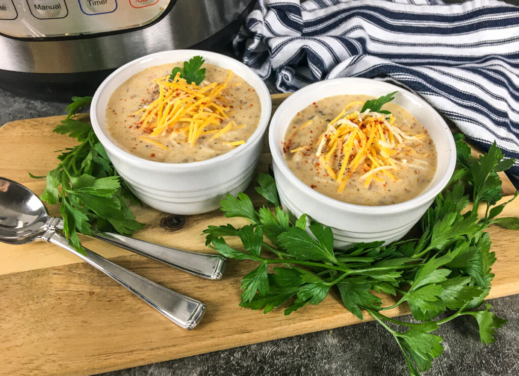 two bowls of Instant Pot Cheeseburger Soup from Flavor Portal recipe in white bowl in front of Instant Pot