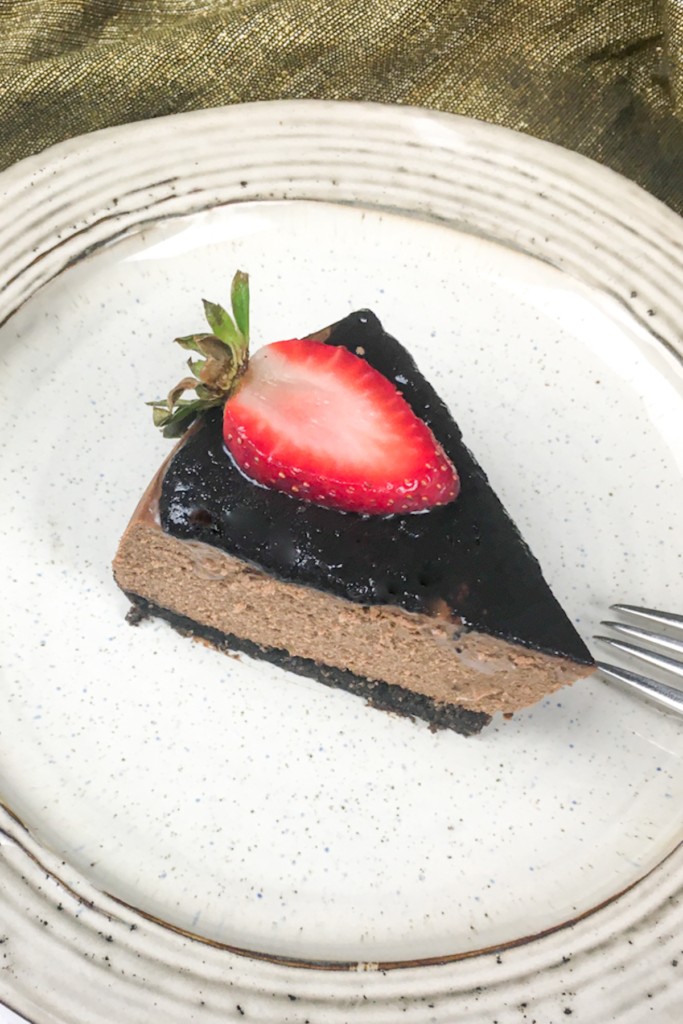 closeup of slice of Instant Pot Chocolate Cheesecake topped with a sliced strawberry