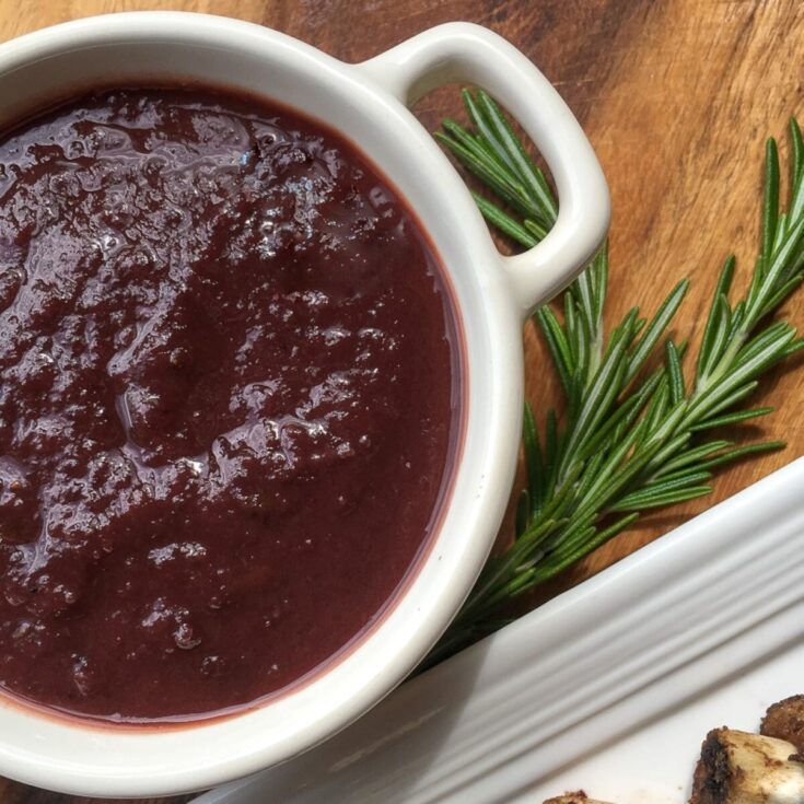 instant pot dark cherry bbq sauce in white bowl next to ribs