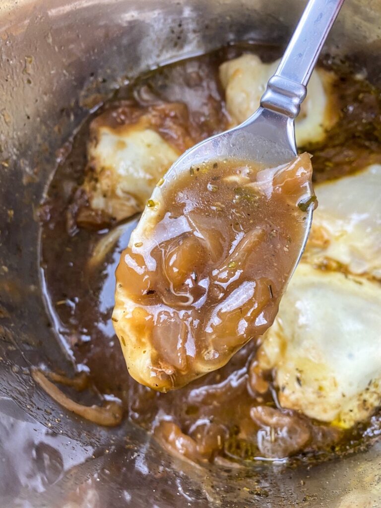 A spoonful of French onion gravy with some melted cheese