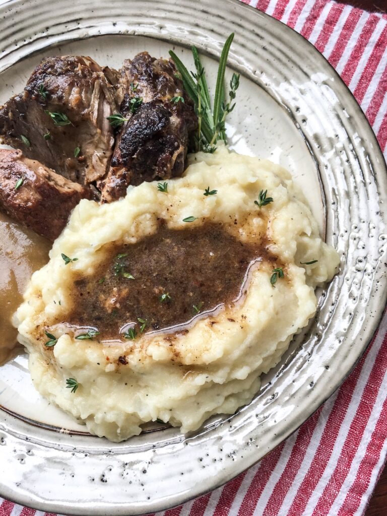 Instant Pot garlic mashed potatoes from Flavor Portal recipe with gravy on a plate with Instant Pot cocoa spiced pork roast
