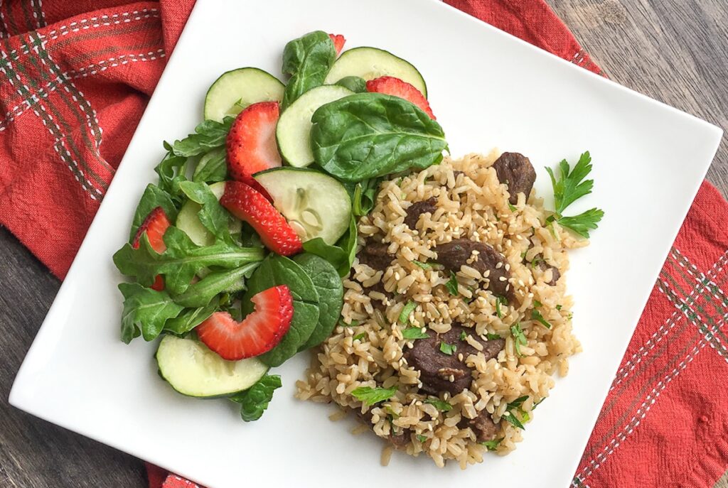 Instant Pot one pot beef and rice from Flavor Portal recipe with a strawberry cucumber salad on a white plate