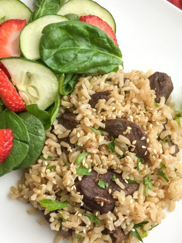 closeup of Instant Pot one pot beef and rice from Flavor Portal recipe with a strawberry cucumber salad on a white plate
