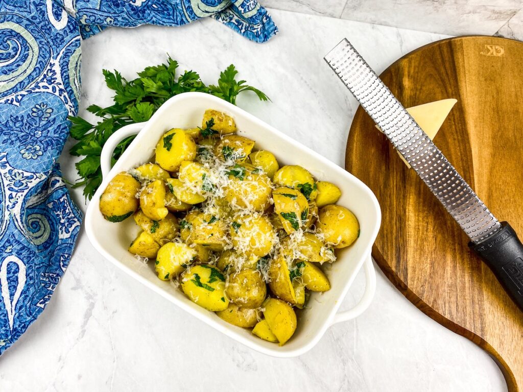 parsley potatoes in white dish next to parmesan and grater flavor portal