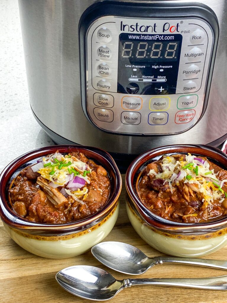 two bowls of Instant Pot pulled pork chili from flavor portal recipe in front of an instant pot
