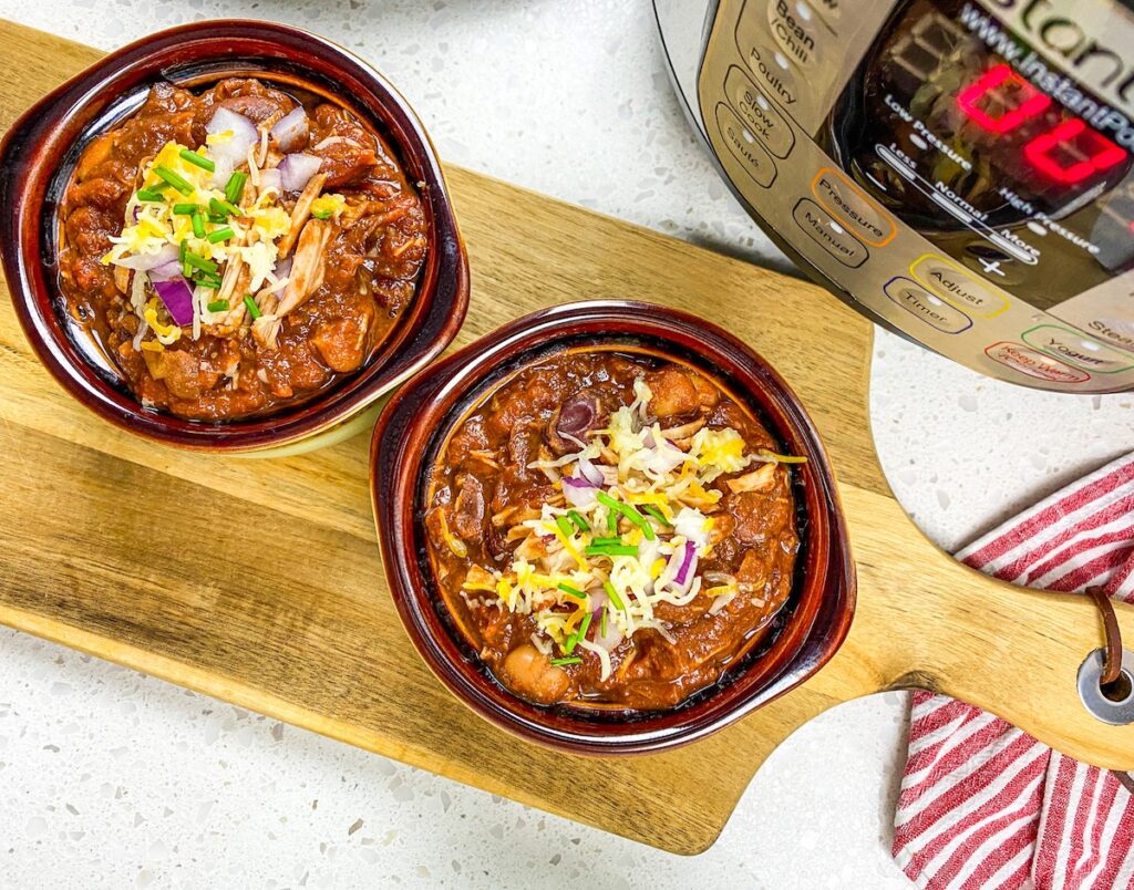 top view two bowls of Instant Pot pulled pork chili from flavor portal recipe in front of an instant pot