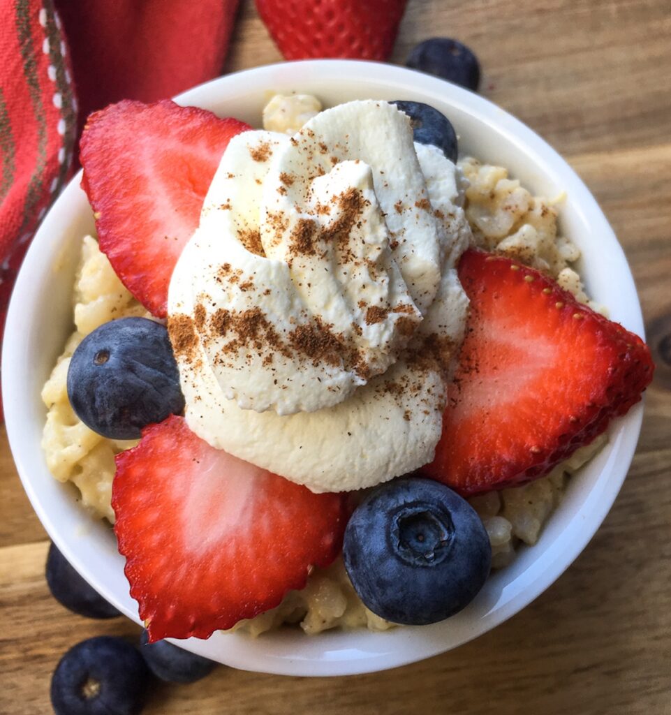 Instant Pot rice pudding from Flavor Portal recipe topped with sliced strawberries, blueberries and whipped cream sprinkled with cinnamon