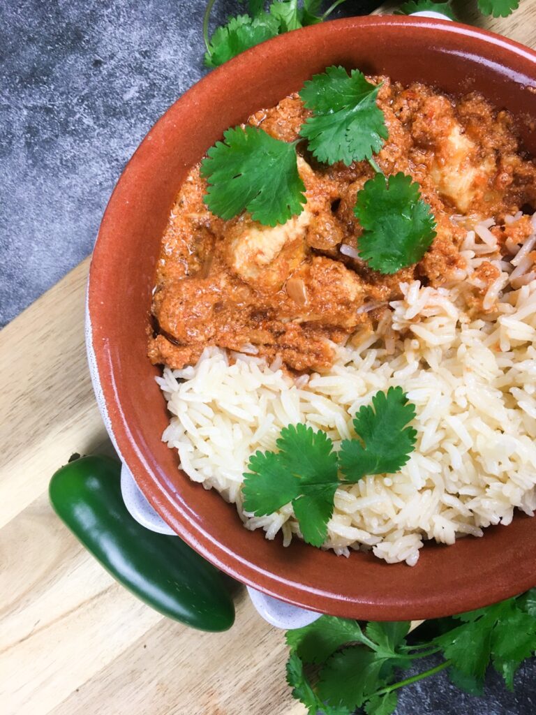 Instant Pot tiki masala from Flavor Portal recipe with rice in a brown ceramic bowl on a wood platter