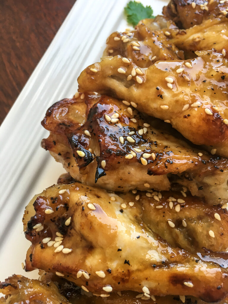 Close up of sesame garlic chicken wings on white background