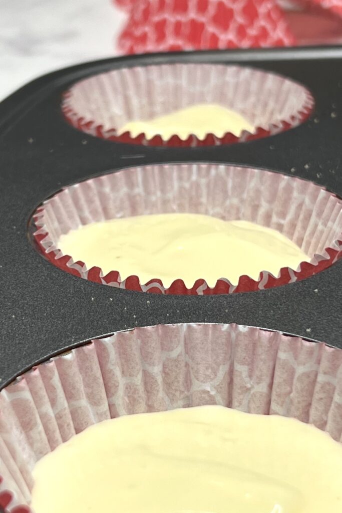 cheesecake mixture in red cupcake liners