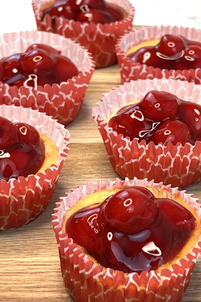 cherry cheesecake tarts with vanilla wafers on a wooden tray