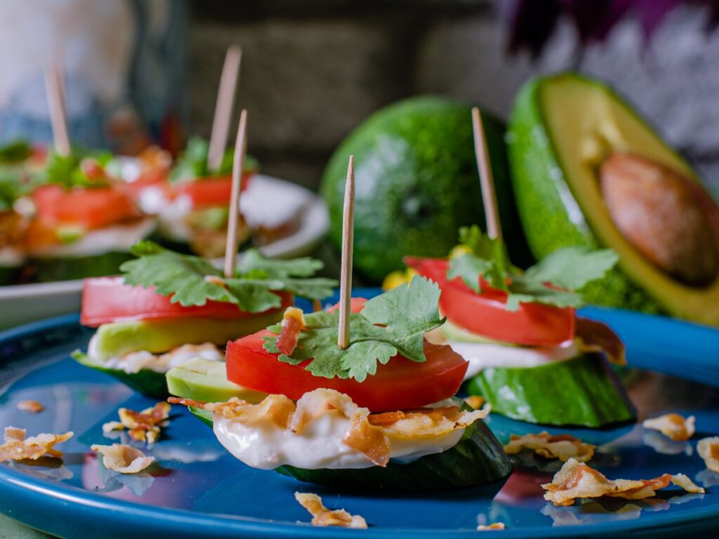 Keto BLT bacon lettuce and tomato bites from Flavor Portal recipe on a wooden board with a sliced avocado