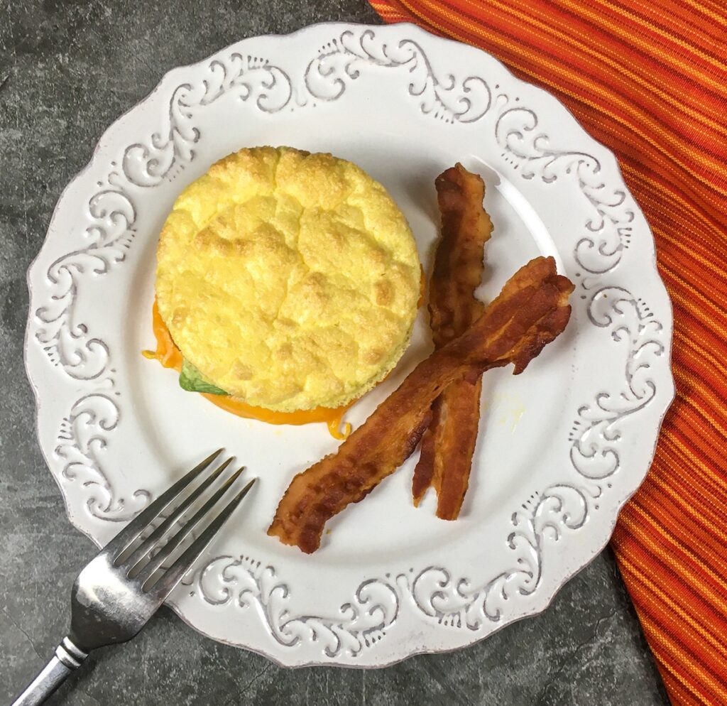 keto breakfast sandwich from Flavor Portal recipe on a white plate with bacon strips
