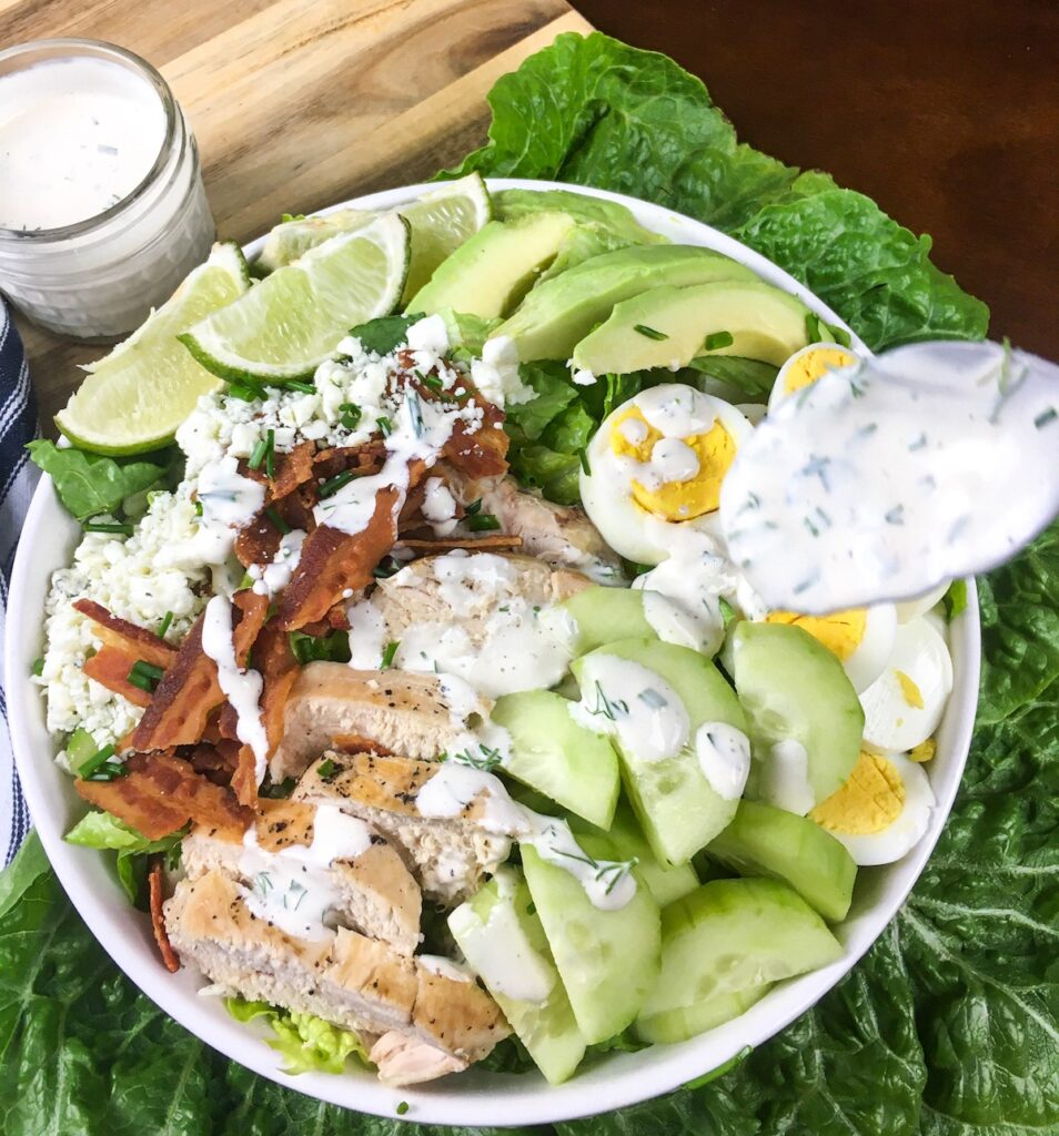 top view keto cobb salad from Flavor Portal recipe in a white bowl next to a jar of dressing